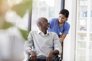 senior man in a wheel chair with young nurse pushing him